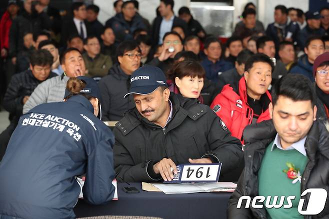 충북 음성 소재 현대건설기계 음성공장에서 중고 굴삭기 경매인 '현대건설기계 옥션'이 진행됐다. 사진은 경매낙찰자가 가계약서에 서명하는 모습. 2017.11.26/ © News1