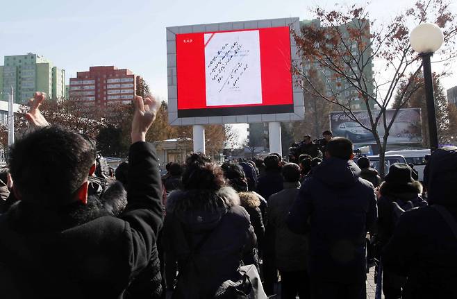 북한 평양 시민들이 29일 낮 시내에서 조선중앙TV의 화성15형 시험발사 보도를 지켜보고 있다. 화면에는 김정은의 화성15형 시험발사 승인 사인이 보인다.[AP=연합뉴스]