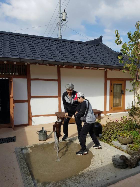 공주 하숙마을을 찾는 한 남성이 아들과 마당에 있는 펌프에서 물을 퍼내고 있다. [공주 하숙마을]
