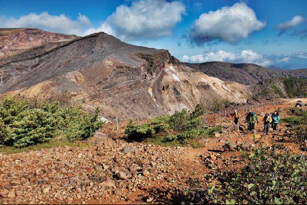 [월간산]3만 년 전 화산폭발 때 날아온 돌멩이가 쌓인 산릉을 오르는 등산인들. 화산재가 쌓인 퇴적층이 바라보인다.