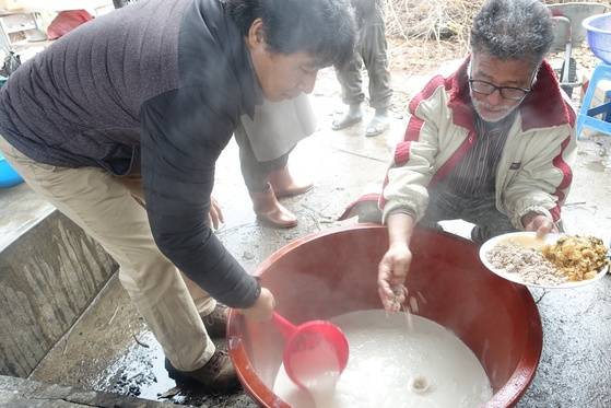 끓인 콩즙을 두부로 굳히기 위해 간수를 질러가며 솥에서 다른 그릇으로 퍼 옮기는 동안 다져서 곤 꿩 뼈를 섞고 있다.