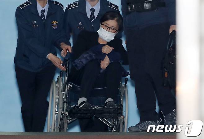 '비선실세' 최순실 씨가 14일 오후 서울 서초구 서울중앙지방법원에서 열린 직권남용권리행사방해 등 결심공판을 마친 뒤 휠체어를 타고 호송차로 향하고 있다. 검찰은 이날 최씨에 대해 25년의 중형과 함께 벌금 1185억원, 추징금 77억 9735억원을 구형했다. 2017.12.14/뉴스1 © News1 민경석 기자