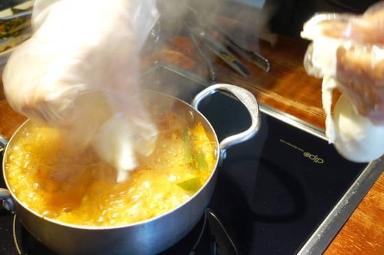 끓는 김치찌개에 수제비를 떠 넣고 있다.