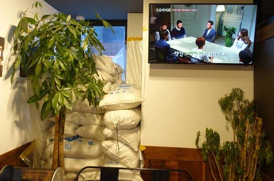 교대점 출입구에 쌓아둔 천일염 자루. ‘육통령’은 저렇게 9년간 간수를 뺀 소금을 쓴다. 옆 TV화면에는 ‘육통령’을 ’바삭한 껍질! 지례 흑돼지 오겹살집“이라고 소개하는 케이블 채널 tvN의 ‘수요미식회’ 방송 내용이 흐르고 있다.