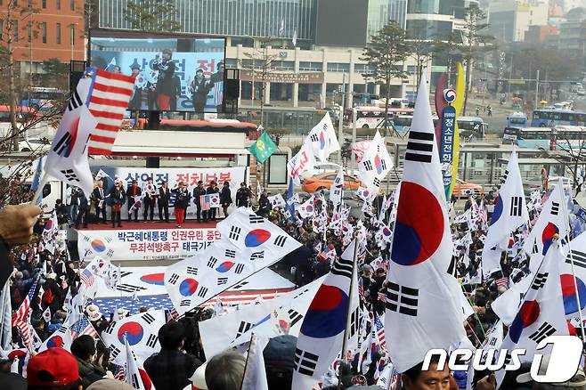 박근혜 전 대통령 무죄석방 서명운동본부 회원들이 23일 오후 서울역 앞에서 태극기와 성조기를 흔들며 박 전 대통령 탄핵 무효와 석방을 촉구하고 있다. 2017.12.23/뉴스1 © News1 황기선 기자