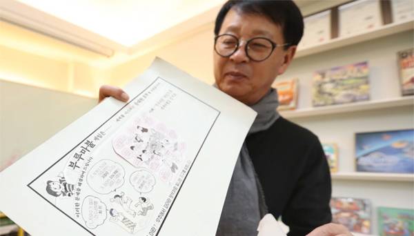 이상배 씨앗사 대표가 이향원 화백이 그려준 부루마불 광고를 들어 보이고 있다.