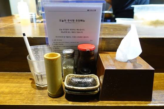 테이블 중간에 놓인 기본 세트. 소스와 덜어 먹을 그릇, 주문지, 오늘의 메뉴 안내판, 휴지가 놓여있다. 대나무는 사용한 꼬치를 담아두는 그릇이다.