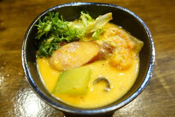 개인 그릇에 덜어놓은 토마토나베. 웃기로 올린 치커리 잎과 토마토·양파·소시지·호박·올리브 등의 재료가 보인다.