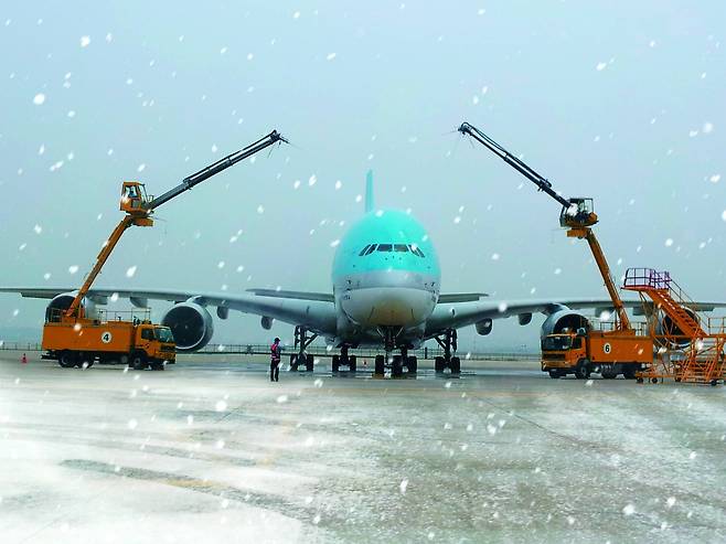 디아이싱 트럭 2대가 대한항공 여객기에 쌓인 눈과 얼음을 제거하고 있다. [사진 대한항공]
