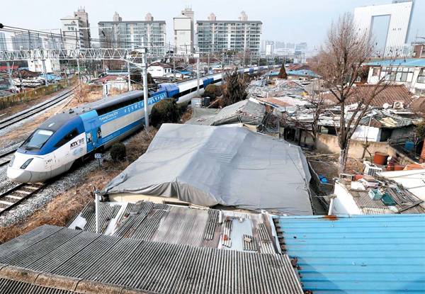 평창으로 향하는 KTX평창 열차가 폐가와 쓰레기 더미로 가득한 용산역 인근 한강로3가 40 일대를 지나가고 있다. 뒤편으로는 최첨단 디자인을 갖춘 서울 드래곤시티의 모습이 보여 뚜렷한 대조를 이루고 있다.  [김호영 기자]