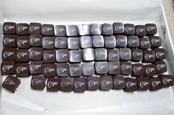 냉각과 건조가 끝난 ‘꿀색’ 초콜릿. 우산을 들고 있는 아이는 한국 출신 벨기에 입양인 만화가 융 에넨의 ‘피부색: 꿀색’이라는 만화의 주인공이다.