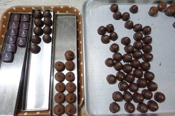 완성된 수제 초콜릿들을 진열장에 내놓을 그릇에 담고 있다.