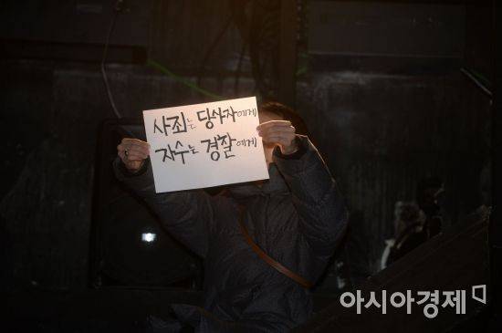 연극 연출가 이윤택 씨가 19일 서울 명륜동 30스튜디오에서 기자회견을 열고 성폭행 논란에 대해 공개 사과하고 있는 가운데 한 시민이 '사죄는 당사자에게 자수는 경찰에게' 문구의 손팻말을 들고 있다. /문호남 기자 munonam@