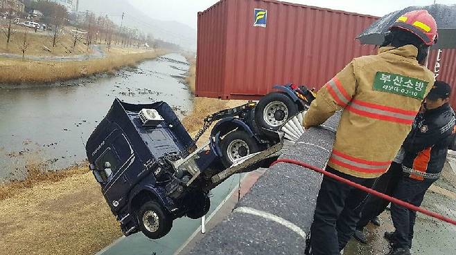 부산의 한 도로에서 보행자를 피하던 트레일러가 미끄러져 5m 아래로 추락했다. 운전자가 타고 있던 차량 앞면은 컨테이너가 도로에 걸려 다행히 바닥에 닿기 직전 멈췄다. (사진=부산경찰청 제공)