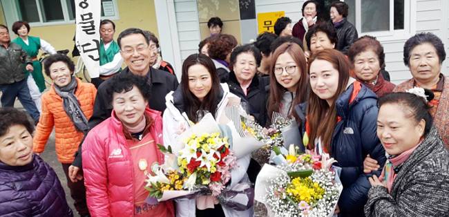지난달 28일 경북 의성군 의성읍 철파리 마을회관에서 열린 환영 마을잔치에서 컬링 여자대표팀의 김영미(앞줄 오른쪽 두 번째부터), 김선영, 김경애가 꽃다발을 들고 주민들과 함께 기념촬영을 하고 있다.  박천학 기자
