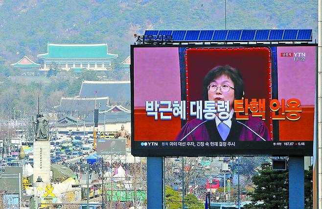 서울 광화문의 대형 전광판에 헌법재판소의 박근혜 대통령 탄핵 심판 인용 결정이 생중계되고 있다. 전광판 옆으로 청와대가 보인다. 조문규 기자