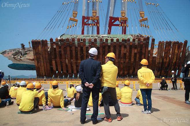 세월호 참사 유가족과 박주민 더불어민주당 의원이 10일 오전 전남 목포신항에서 옆으로 누워있던 세월호 바로 세우기 작업을 지켜보고 있다. ⓒ유성호