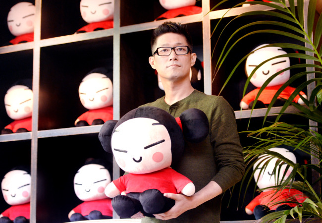 Art Director Kim Boo-kyoung poses with a Pucca doll at Puccafe in southern Seoul. (By Park Hyun-koo / The Korea Herald)