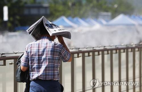 '아, 더워' (서울=연합뉴스) 신준희 기자 = 때이른 무더위가 찾아온 1일 오후 서울 광화문광장을 지나는 시민이 신문지로 햇빛을 가린 채 쿨링포그 옆을 지나고 있다. 2018.6.1 hama@yna.co.kr