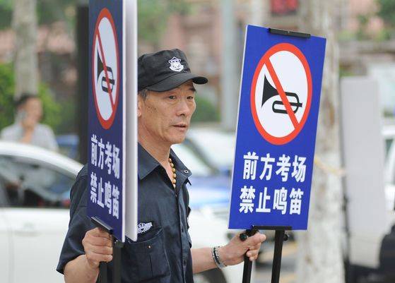중국 칭다오의 한 시험장소 인근에서 안전요원이 경적금지 사인을 들고 있는 모습.[연합뉴스]