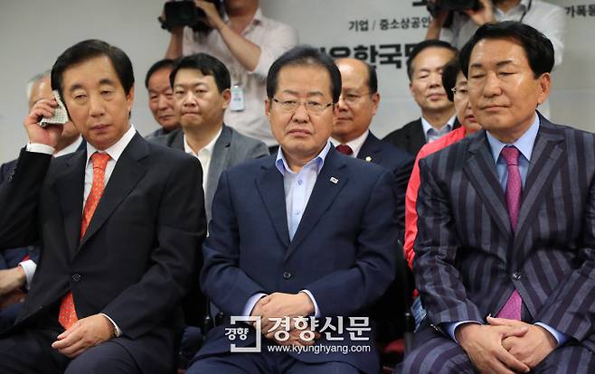 자유한국당 홍준표 대표(가운데)가 김성태 원내대표(왼쪽) 등 당직자들과 함께 13일 선거가 끝난 뒤 당사에서 방송사들의 출구조사 결과를 시청하며 침통한 표정을 짓고 있다. 김영민 기자