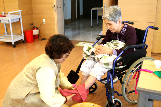 한 요양보호사가 여자 어르신의 발을 닦아주고 있다. [사진 대정요양병원]