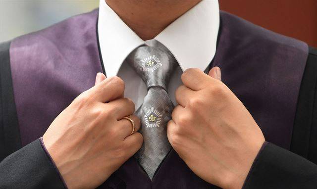 남성 법관은 흰색 셔츠에 은회색 넥타이를 맨다.
