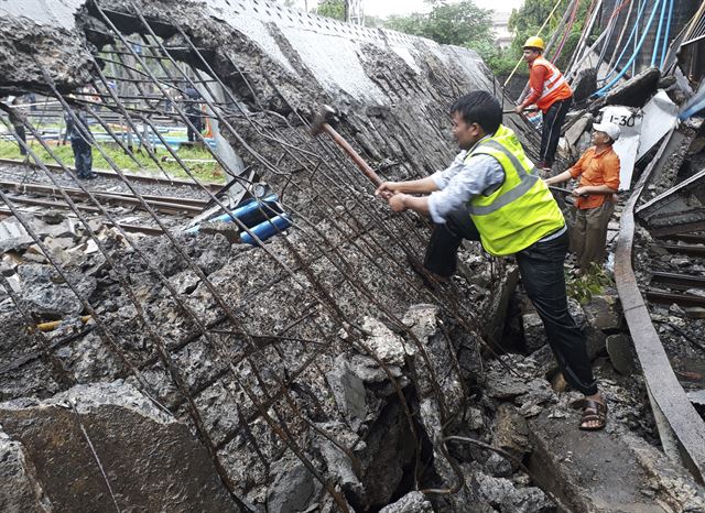 인도 뭄바이에서 3일(현지시간) 폭우로 인한 기역에서 보도교 붕괴사고가 발생한 가운데 구조요원들이 수습작업을 하고 있다. 이번 사고로 최소 2명이 부상을 당했다. AP 연합뉴스