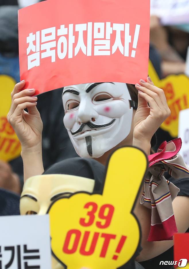 가면을 쓴 아시아나항공 직원들이 8일 저녁 서울 종로구 세종문화회관 앞 계단에서 열린 ‘아시아나항공 No Meal(노 밀) 사태 책임 경영진 규탄 문화제’에서 '침묵하지 말자' 현수막을 들고 있다. 이날 집회 참여자들은 박삼구 회장의 사퇴를 요구하며 ‘승객·직원 굶기는 갑질삼구 OUT’ ‘39 OUT!’ 등이 적힌 피켓을 들었다. © News1 송원영 기자