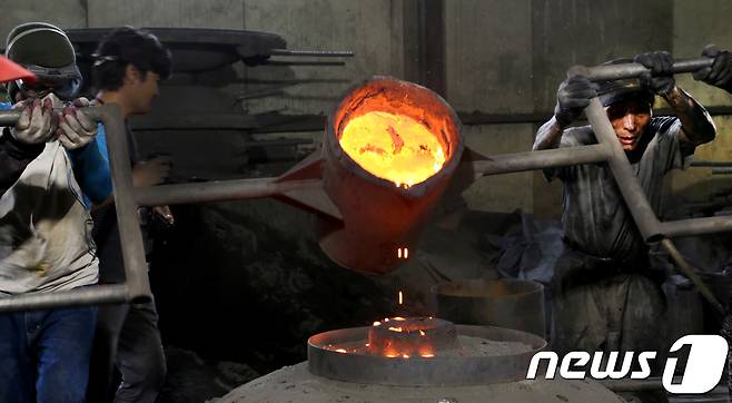 29일 경북 구미시 고아읍 사랑채 가마솥공장 직원들이 1500도 용광로에서 녹인 쇳물을 지름 1m의 대형 가마솥 거푸집사이로 붓고 있다.2018.7.29/뉴스1 © News1 정우용 기자