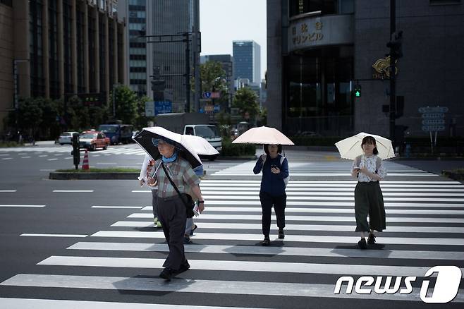 지난달 23일, 일본 도쿄에서 시민들이 더위를 피해 양산을 쓴 채 걸어가고 있다. © AFP=뉴스1