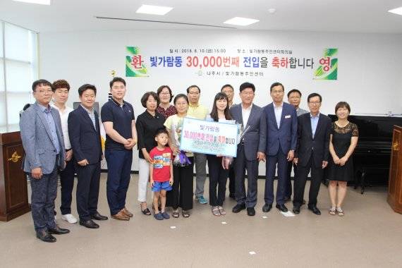 강인규 나주시장이 빛가람동 전입 3만 번째 주인공이 된 주민 박주영씨 가족에게 꽃다발과 상품을 전달하고 기념촬영을 하고 있다.