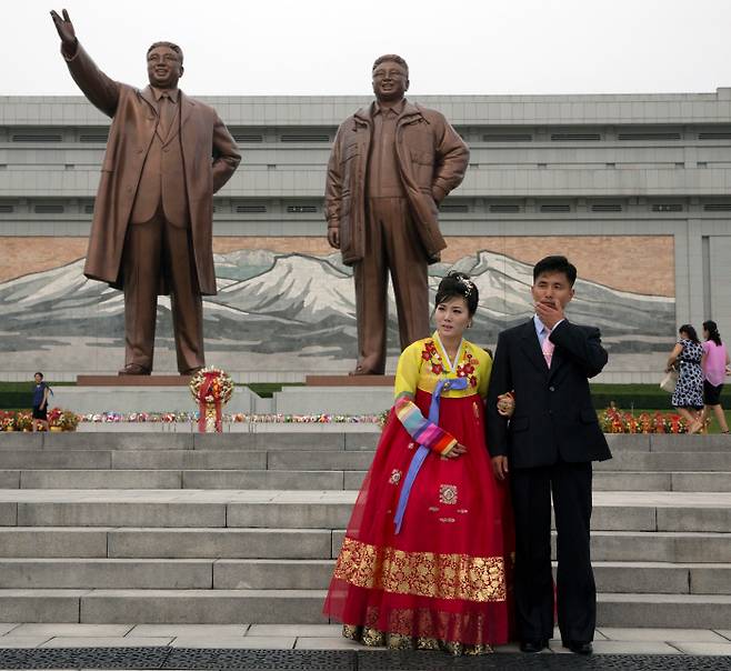 우리 방금 결혼했어요 북한의 한 신혼부부가 ‘조국해방기념일’로 불리는 15일 평양 만수대에 자리한 김일성 주석과 김정일 국방위원장 동상 앞에서 기념사진을 찍고 있다.  평양 | AP연합뉴스