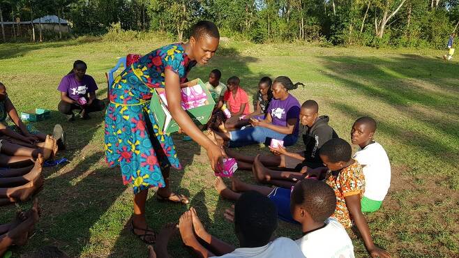 케냐 미고리주 쿠리아 이커리지 마을의 교회 공원에서 ‘미스차나 쿠리아 임파워먼트’(MEK) 활동가들이 가져간 생리대를 여성청소년들에게 나눠주고 있다.