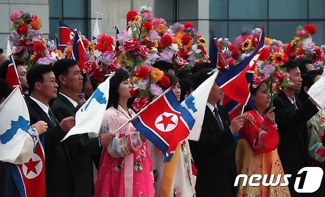 18일 오전 문재인 대통령의 평양 순안공항도착을 환영하기위해 한반도기와 인공기를 든 평양시민들의 모습이 서울 중구 동대문디자인플라자에 마련된 메인프레스센터에 문재인 대통령과 생중계 되고 있다. 2018.9.18/뉴스1 © News1 송원영 기자