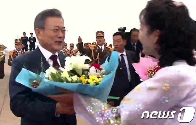 문재인 대통령이 20일 오전 백두산 방문을 위해 순안공항에 도착해 전용기로 향하며 꽃다발을 받는 모습이 서울 동대문디자인플라자(DDP)에 마련된 평양 남북정상회담 메인프레스센터에서 중계되고 있다. 2018.9.20/뉴스1 © News1 송원영 기자