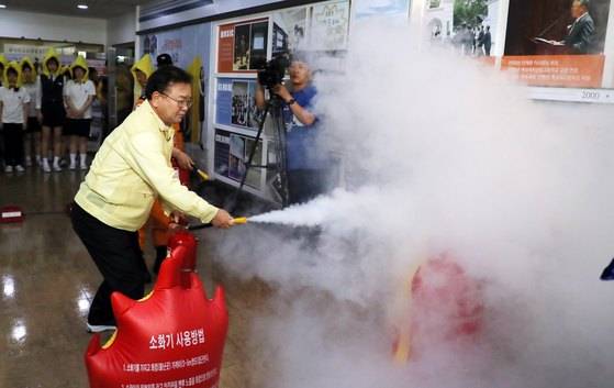 김부겸 행정안전부 장관이 지난 5월16일 오후 서울 동대문구 해성국제컨벤션고등학교에서 열린 '2018 재난대응 안전한국훈련 지진대피훈련'에서 소화기를 이용한 화재 진압법을 체험하고 있다. [뉴스1]