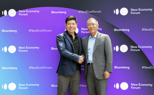 Hyundai Motor Chief Vice Chairman Chung Eui-sun (right) shake hands with Grab founder and CEO Anthony Tan at a forum in Singapore on Tuesday after agreeing to invest $250 million in the ride-hailing service. (Hyundai Motor)