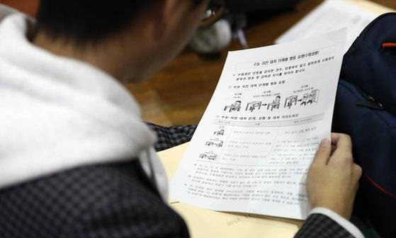 수능을 하루 앞둔 14일 오후 경북 포항고등학교에서 진행된 예비소집에서 수험생이 지진 발생 시 단계별 행동 요령을 확인하고 있다. [연합뉴스]