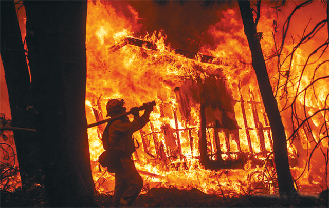 미국 캘리포니아주 북부 마갈리아에서 최근 한 소방관이 온통 화염에 휩싸인 주택 화재 현장에서 불에 탈 듯 가까운 거리까지 접근해 화재 진압 작업을 벌이고 있다. 마갈리아=AP 뉴시스