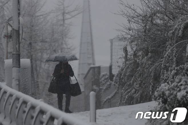24일 서울 종로 거리를 지나는 시민이 첫 눈 사이로 발걸음을 옮기고 있다. 기상청은 서울과 경기 북부에 대설주의보를 발령했다. 2018.11.24/뉴스1 © News1 박정호 기자