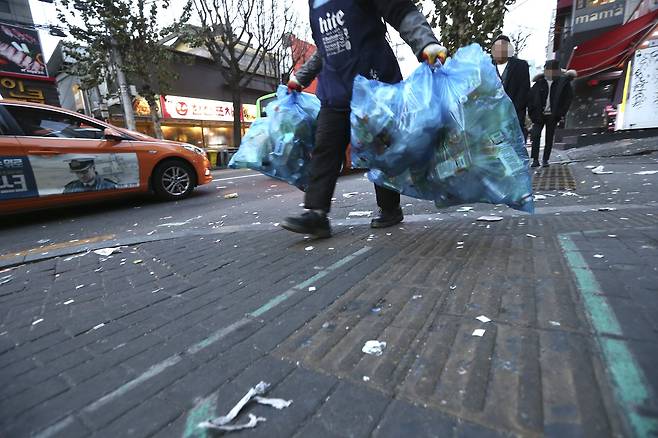 한 매장 직원이 25일 오전 서울 마포구 홍대 거리에서 쓰레기를 치우고 있다. 임현동 기자