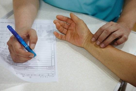 한의사의 진료 모습. 절진이란 배를 눌러보는 복진, 등을 눌러보는 배진, 여기저기 눌러보는 압진 외에 맥상을 파악하는 맥진으로 나뉜다. 손목의 맥을 잡는 것은 5분의 1 정도를 확인하는 방법이다. [중앙포토]