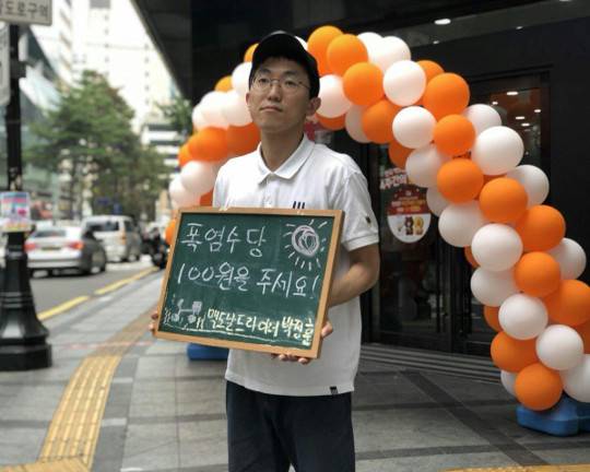 ‘이것은 왜 직업이 아니란 말인가’의 저자인 박정훈씨는 지난여름 한 맥도날드 매장 앞에서 1인 시위를 벌였다. 맥도날드 라이더(배달 노동자)인 그는 당시 사측을 상대로 폭염수당 지급을 요구해 화제가 됐다. 오른쪽 작은 사진은 배달할 때 착용하는 헬멧을 쓰고 포즈를 취한 박씨.  신유아 제공