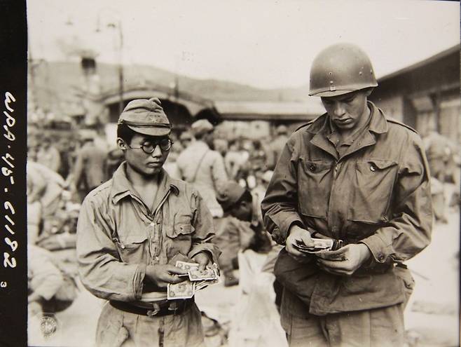 1945년 10월12일 부산항에서 미군이 일본으로 돌아가는 배를 기다리는 일본군 한명이 소지한 현금을 점검하고 있다. 일본으로 송환되는 일본인이 소지할 수 있는 돈은 민간인은 1000엔, 군 장교는 500엔, 사병은 250엔이 상한선이었다. 미국 국립문서관, 국사편찬위 전자사료관 사본