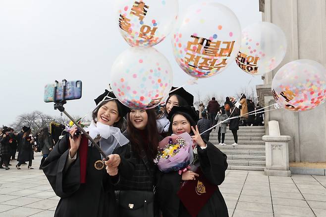 경희대학교 2018학년도 학위 수여식이 열린 20일 오전 서울 동대문구 캠퍼스 평화의전당 앞에서 졸업생들이 풍선을 들고 셀카를 찍고 있다. [연합뉴스]