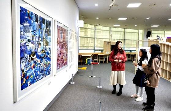 조화순(왼쪽) 사서가 학생기자단에게 '성평등도서관 갤러리' 작품을 소개하고 있다. 학생기자들은 파란색 배경에 있는 소년과 분홍색 배경에 있는 소녀 그림의 문제가 뭔지 단번에 맞혔다.