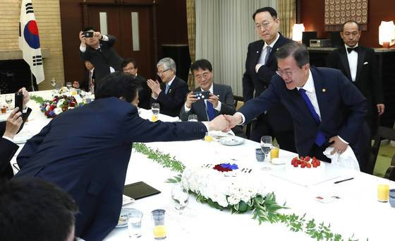 문재인 대통령(오른쪽)이 지난해 5월 9일 일본 도쿄 총리공관에서 열린 한일 정상회담 오찬에서 아베 신조 일본 총리로부터 대통령 취임 1주년 기념 축하 케이크를 받은 뒤 총리와 악수하고 있다.청와대사진기자단