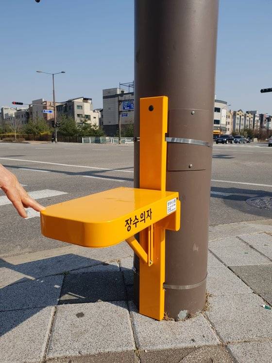 횡단보도 앞에 설치된 장수의자. 높이를 노인 앉은 키에 맞추고, 등받이에 고무 쿠션을 부착해 노인이 앉기 편안하게 제작했다.스테인리스 재질로 무게 100kg까지 감당할 수 있다.［사진 별내파출소］