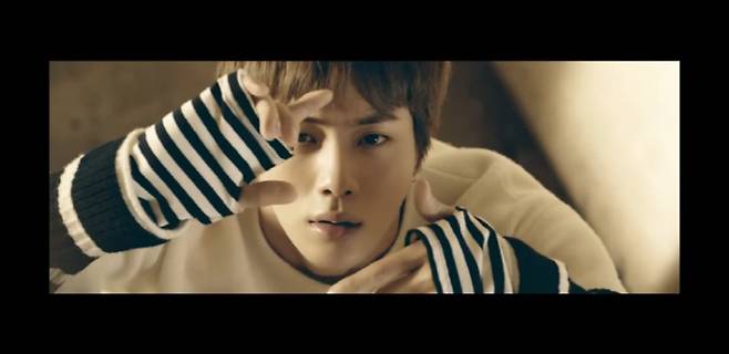 방탄소년단 ‘봄날’ 뮤직비디오에서는 해맑게 뛰어노는 6명의 친구들을 따라가지 않고 손을 들어 카메라를 찍는 포즈를 보이는 석진의 모습이 등장한다. 이는 시간을 멈추거나 되돌릴 수 있는 석진의 타임리프 능력을 상징한다는 해석이 많았다. (사진=‘봄날’ 뮤직비디오 장면 캡쳐)